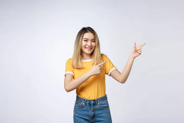Güzel genç Asyalı kadın beyaz arka plan üzerinde neşeli ifade ile parmağıyla yukarıyı. — Stok fotoğraf