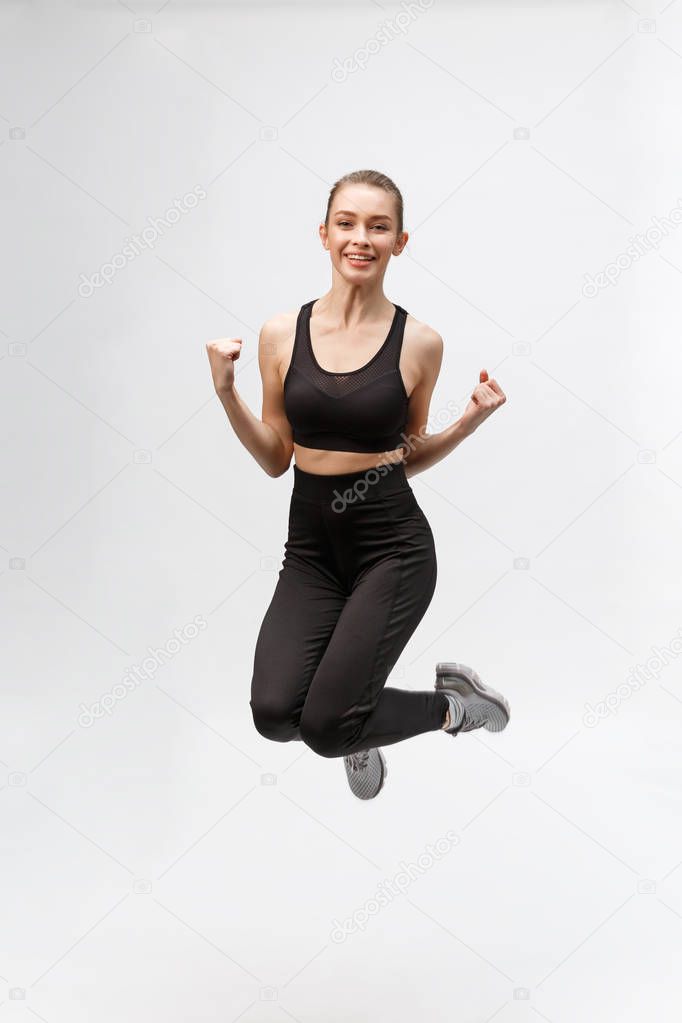 Full length picture of happy beautiful fitness woman over gray background