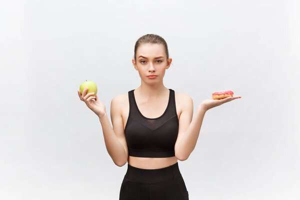 Young woman choosing between donut and apple on white background. Diet food concept