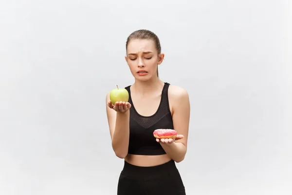 Beyaz arka planda çörek ve elma arasında seçim yapan genç bir kadın. Diyet gıda konsepti — Stok fotoğraf