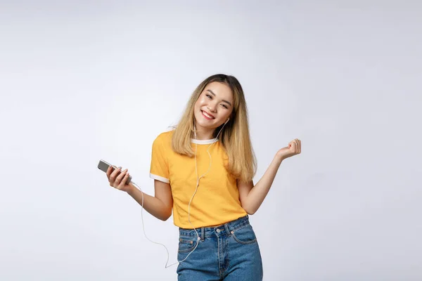 Retrato de una alegre mujer asiática satisfecha en auriculares escuchando música y saltando aislado sobre fondo blanco — Foto de Stock