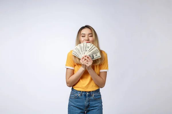 Asiatin mit Geldscheinen auf weißem Hintergrund. junge asiatische Frau in weißem T-Shirt in gewinnender Überraschung, mit Dollarschein. junge reiche Hipster-Konzept. — Stockfoto