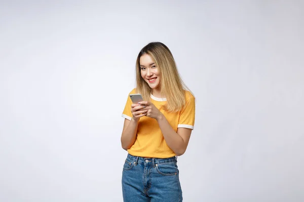 Mujer mirada y mensajes de texto con amigo en el teléfono móvil aislado sobre fondo gris . — Foto de Stock