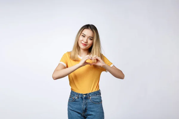 Muito jovem mulher asiática fazendo um gesto de coração com os dedos na frente de seu peito — Fotografia de Stock