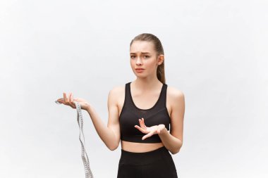 Elinde mezura tutan üzgün bir kadının portresi beyaz arka planda izole edilmiş kameraya bakıyor.