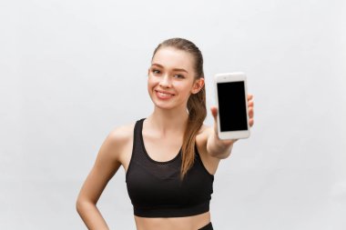 Spor kıyafetli kadın beyaz arka planda izole edilmiş bir telefon gösteriyor.