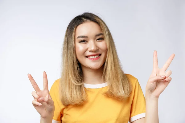 Mujer asiática joven feliz mostrando dos dedos o gesto de victoria con espacio de copia en blanco para el texto, Retrato de hermosa mujer asiática aislada sobre fondo blanco —  Fotos de Stock