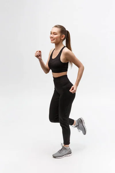 Imagen completa de una mujer deportiva corriendo en el estudio sobre fondo gris . — Foto de Stock