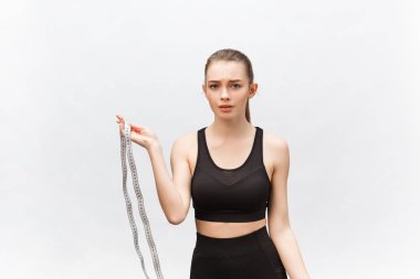 Elinde mezura tutan üzgün bir kadının portresi beyaz arka planda izole edilmiş kameraya bakıyor.