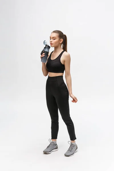 Retrato de una joven deportista sana sosteniendo una botella de agua aislada sobre un fondo blanco — Foto de Stock