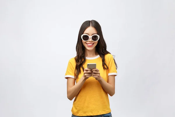Content calm trendy nice cute adorable lovely attractive brunette caucasian girl with wavy hair in casual shirt, playing game in phone, isolated over grey background. — Stock Photo, Image
