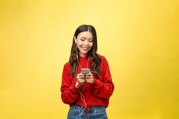 Retrato de una mujer feliz escuchando música en auriculares y bailando aislada sobre un fondo amarillo — Foto de Stock