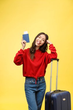 Kadın seyahati. Sarı arka planda bavulu ve pasaportu olan güzel Asyalı kadın gezgin.