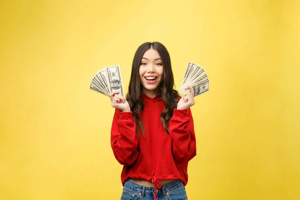 Крупный план молодой красивой женщины с нами долларовые деньги в руке на желтом фоне, с копировальным местом — стоковое фото