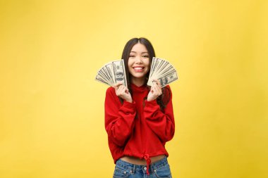 Genç ve güzel bir kadının yakın plan fotoğrafı. Para elimizin altında. Sarı arka plan, fotokopi alanı.