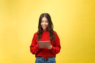 Tablet bilgisayarlı mutlu genç kızın fotoğrafı sarı arkaplanda izole edilmiş.