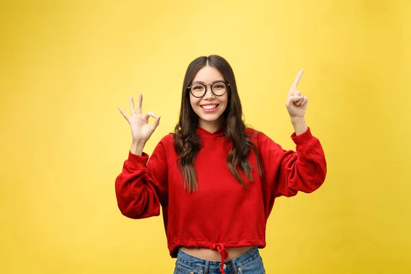 Jovem bela mulher asiática apontando para copyspace, isolado no fundo amarelo — Fotografia de Stock