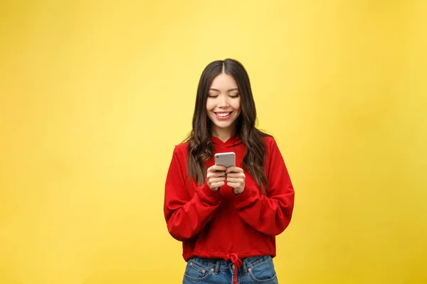 Joven hermosa mujer feliz usando el teléfono inteligente. Aislado sobre fondo amarillo — Foto de Stock