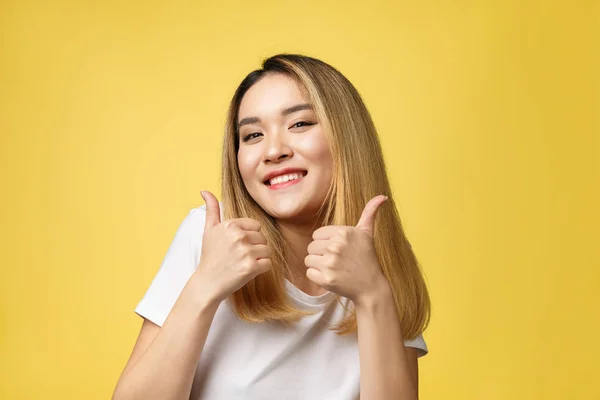 Joven mujer asiática mostrar pulgares hacia arriba en amarillo fondo — Foto de Stock