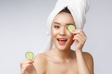 Beyaz arka planda salatalıkla cilt bakımı yapan güzel Asyalı kadınlar..