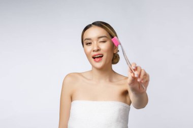 Beyaz arka planda yaşayan güzel genç bir kadın diş fırçası tutuyor, Asyalı.