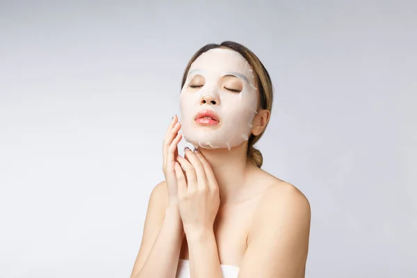 Hermosa asiático mujer aplicación papel hoja máscara en su cara blanco fondo —  Fotos de Stock