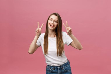 İki parmak gösterilen neşeli bir moda kadın portresi oturum pembe arka plan üzerinde