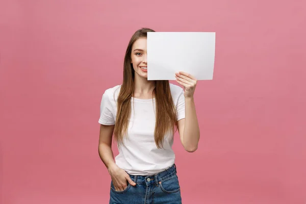Close up portrait of positive laughing woman smiling and holding white big mockup poster isolated on pink background — Stock Photo, Image
