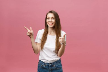 Kadın kamerayı işaret ediyor ve dişlek gülümsüyor. İfade duygusu ve duygular kavramı. Stüdyo çekimi, pembe arka planda izole edilmiş.