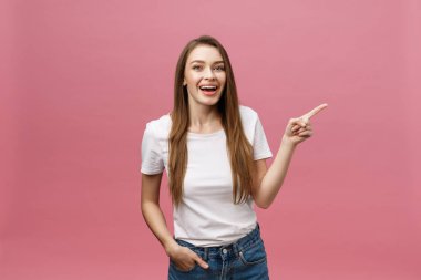 Kadın kamerayı işaret ediyor ve dişlek gülümsüyor. İfade duygusu ve duygular kavramı. Stüdyo çekimi, pembe arka planda izole edilmiş.