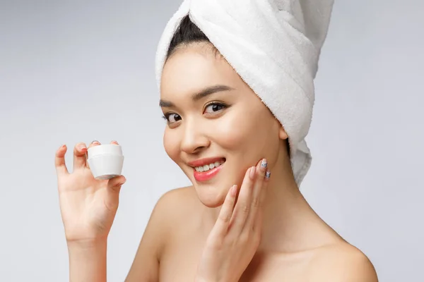 Egészség és szépség koncepció - Vonzó ázsiai nő alkalmazó krém a bőrén, elszigetelt fehér. — Stock Fotó