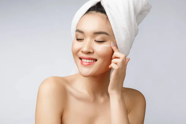 Zdraví a krása koncept - Atraktivní asijské žena nanášení krému na kůži, izolované na bílém. — Stock fotografie