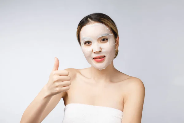 Spa, soins de santé. Asiatique fille avec un cosmétique masque avec montrant pouce vers le haut. — Photo