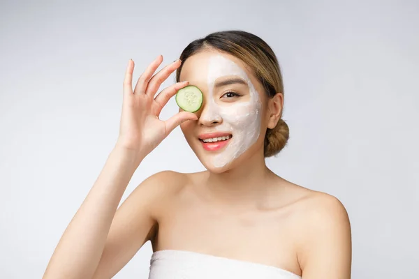 Asian young beautiful smiling woman with flawless complexion holding cucumber slices over eye. — Stock Photo, Image