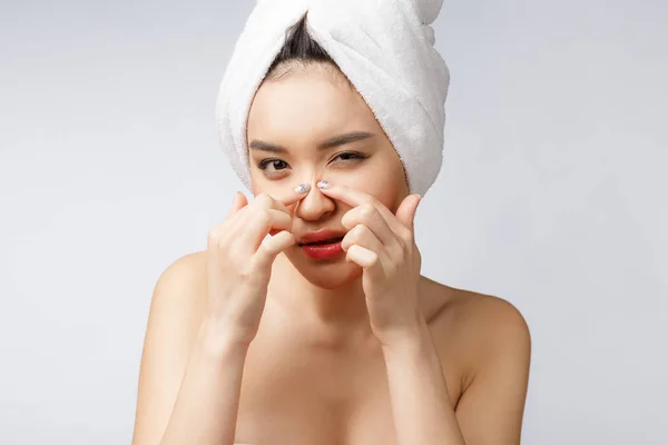 Azjatka patrząca na pryszcza na twarzy. Młoda kobieta próbuje usunąć pryszcz. Kobieca koncepcja pielęgnacji skóry. Izolacja na białym tle — Zdjęcie stockowe