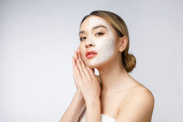 Charming pleasant woman applying cream on half face. — Stock Photo, Image