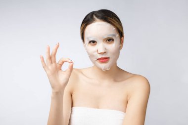 Spa, sağlık hizmeti. Kozmetik maskeli Asyalı kız beyazın üzerinde izole edilmiş..