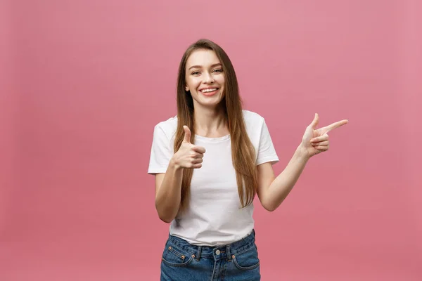 Foto van gelukkige jonge vrouw staande en wijzende vinger geïsoleerd over roze achtergrond. — Stockfoto