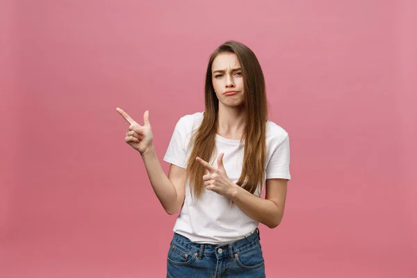 Primer plano de la mujer joven estricta seria lleva camisa blanca se ve estresado y apuntando hacia arriba con el dedo aislado sobre el fondo rosa —  Fotos de Stock