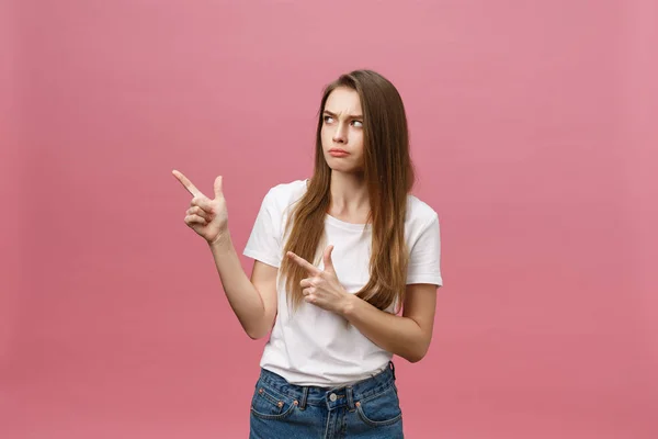 Ciddi derecede sıkı giyinen, beyaz gömlek giyen, gergin görünen ve pembe arka planda izole edilmiş parmaklarıyla işaret eden genç bir kadın. — Stok fotoğraf