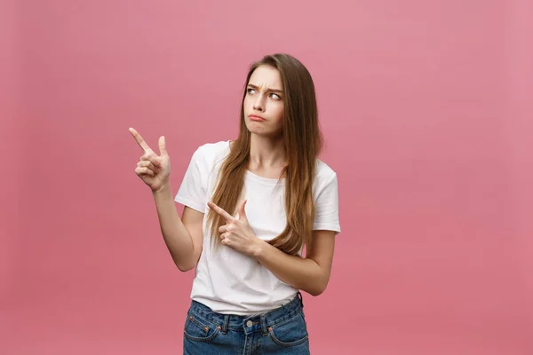 Primer plano de la mujer joven estricta seria lleva camisa blanca se ve estresado y apuntando hacia arriba con el dedo aislado sobre el fondo rosa —  Fotos de Stock