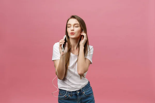 Lifestyle Concept. Jeune femme utilisant le téléphone pour écouter de la musique sur fond rose — Photo