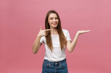 Ayrı pembe arka planda bir ürün sunmak için beyaz gömlekli genç kız el ele tutuşuyor.