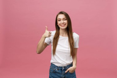 Mutlu genç bir kadın pembe arka planda başparmak kaldırıyor..