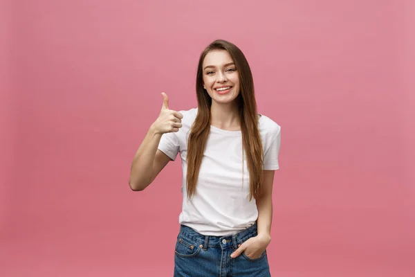 Gelukkig jong vrouw geven duimen omhoog op roze achtergrond. — Stockfoto