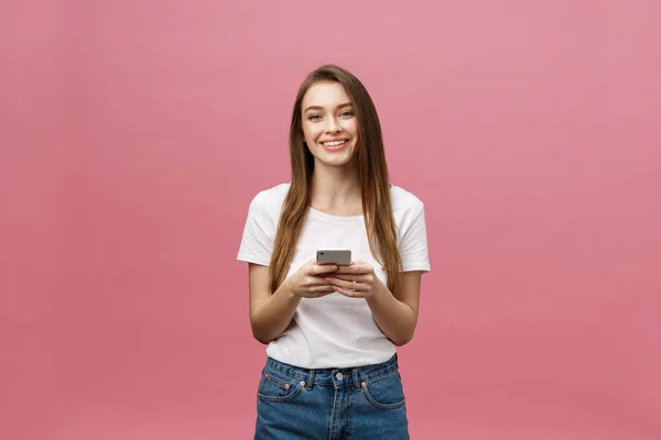 Foto av glad söt vacker ung kvinna chatta med mobiltelefon isolerad över rosa vägg bakgrund. — Stockfoto
