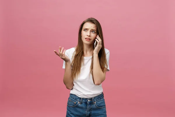Serieuze jonge vrouw praten over telefoon geïsoleerd op roze. Kopieer ruimte en mode. Mock up. — Stockfoto