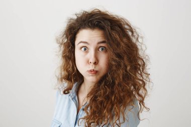 Portre beyaz arka plan üzerinde izole duran sürpriz genç kadın heyecan. Görünümlü kamera.