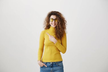 Onun parmak gri arka plan üzerinde izole boş yere doğru işaret heyecanlı genç kadın.