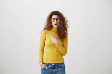 Onun parmak gri arka plan üzerinde izole boş yere doğru işaret heyecanlı genç kadın.